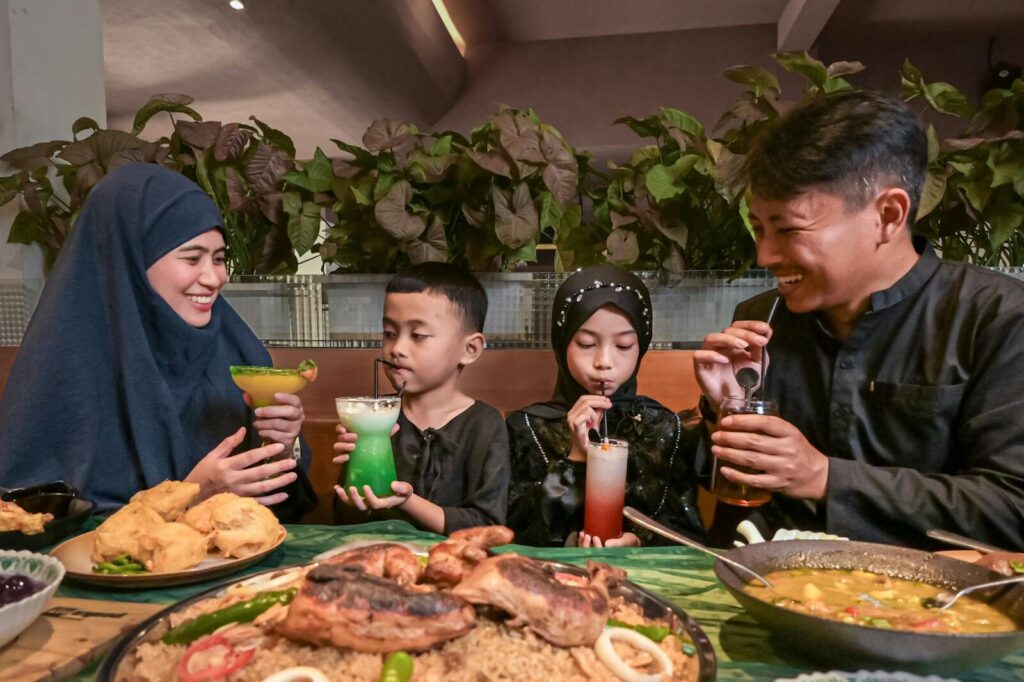A family sharing drinks and traditional food in an Indonesian restaurant, featuring a warm and joyful atmosphere.