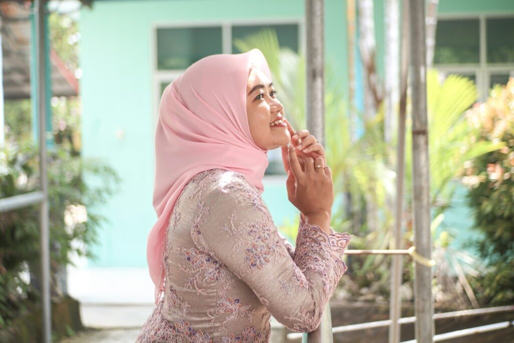 A woman in a hijab smiles thoughtfully.