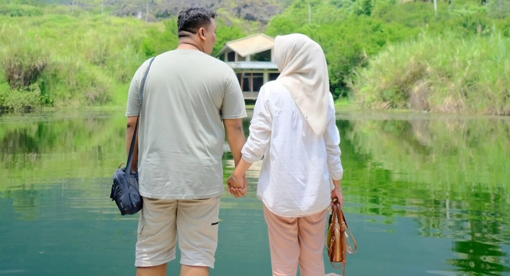 A couple holds hands near a beautiful lake.
