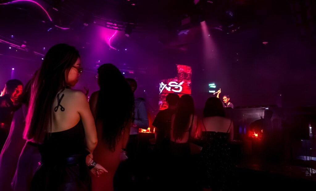 People are dancing in a crowded, lit nightclub.