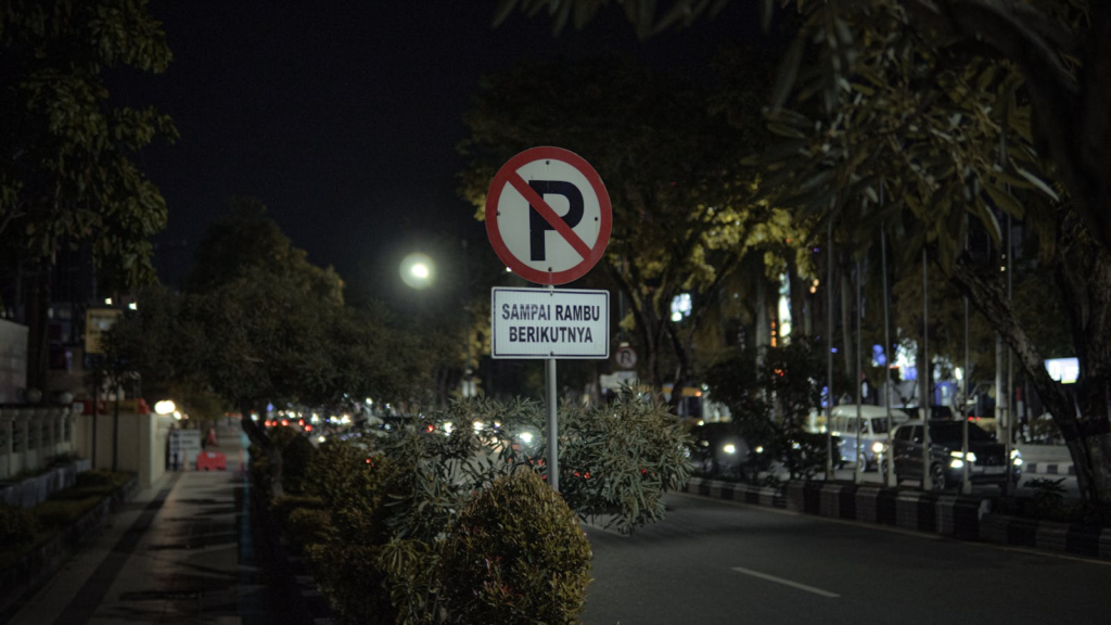 City street at night featuring a no parking sign with light traffic.