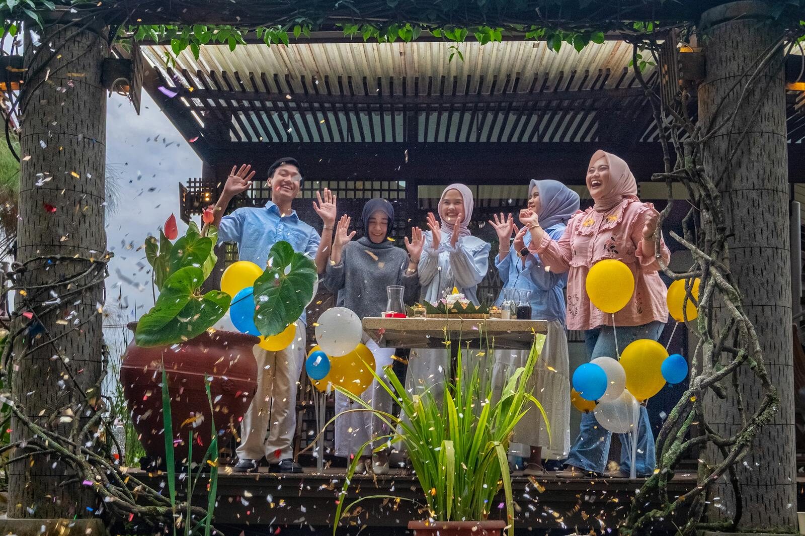 A joyful outdoor celebration in Jawa Barat, Indonesia with confetti and balloons, capturing happiness.