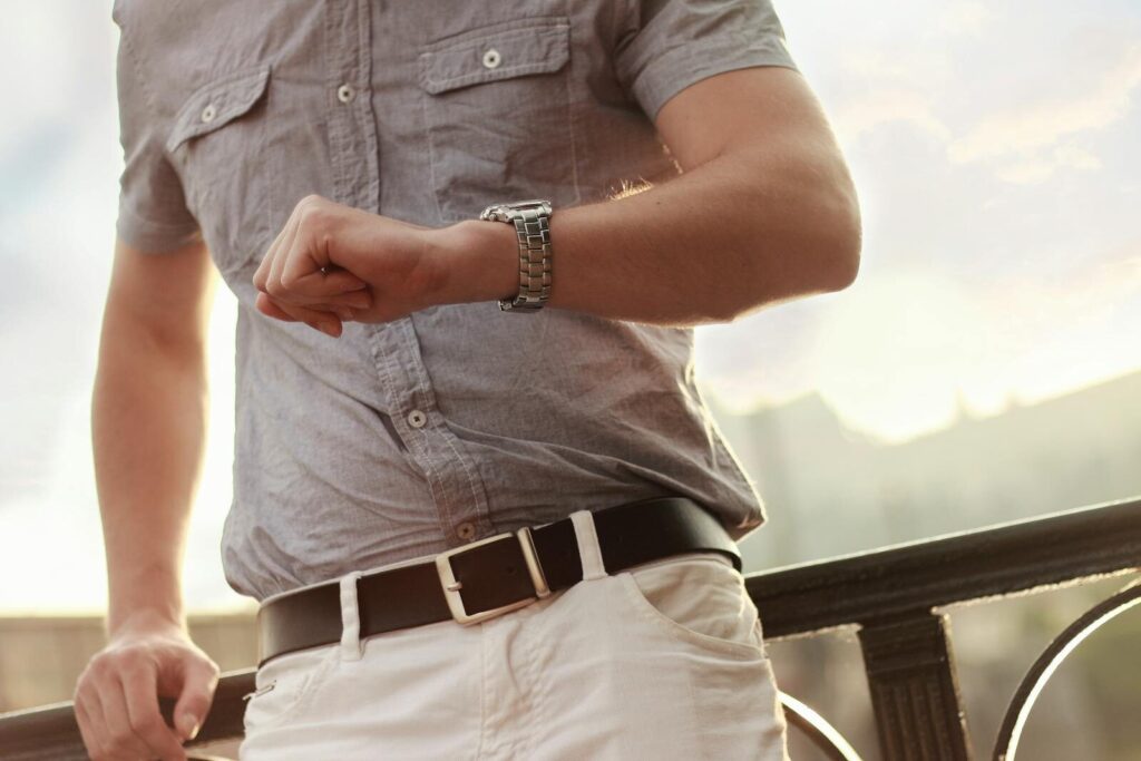 Close-up of an adult man checking his wristwatch outdoors.