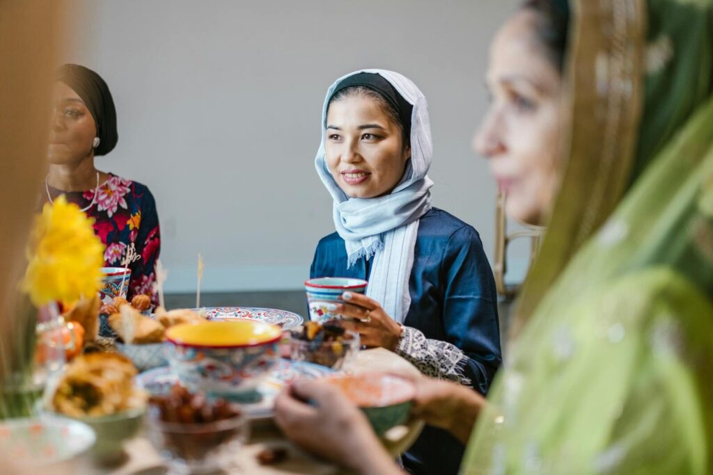 Women enjoying a Ramadan meal, sharing smiles and cultural traditions indoors.
