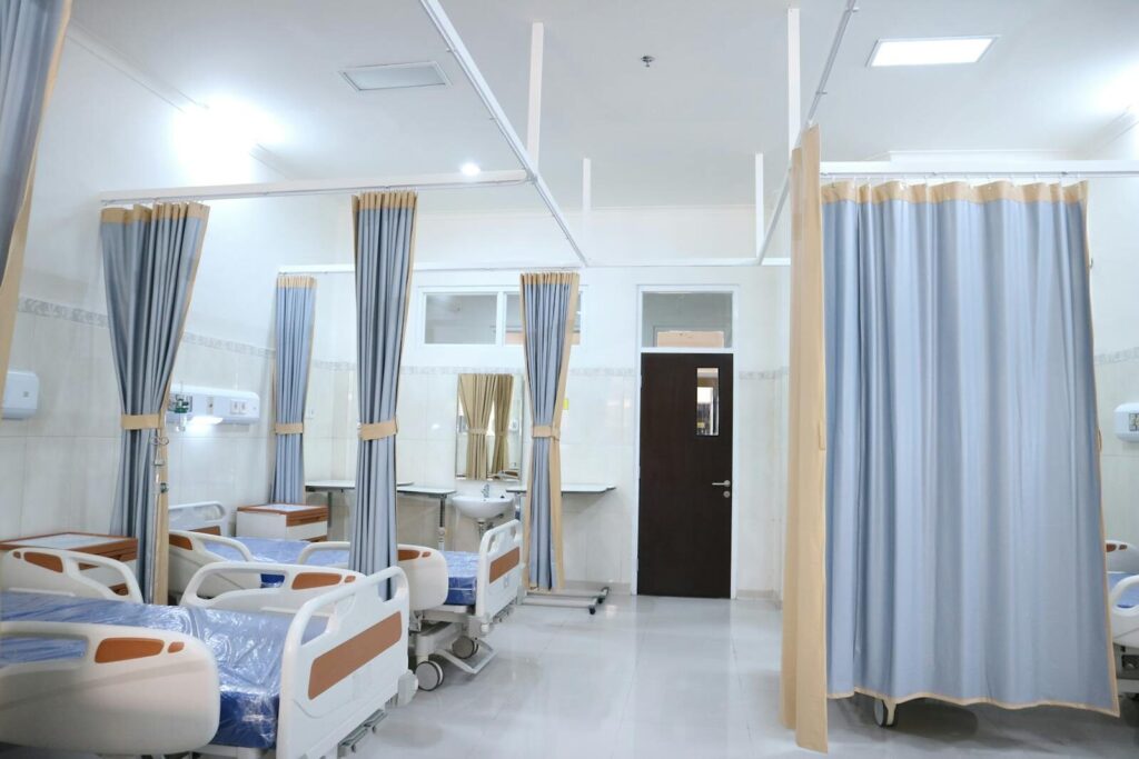Clean and modern hospital ward with beds and privacy curtains in Surabaya, Indonesia.