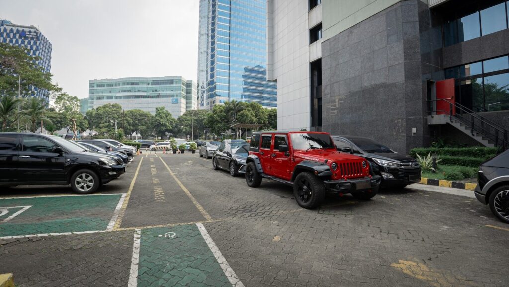Several cars parked in a lot near buildings.