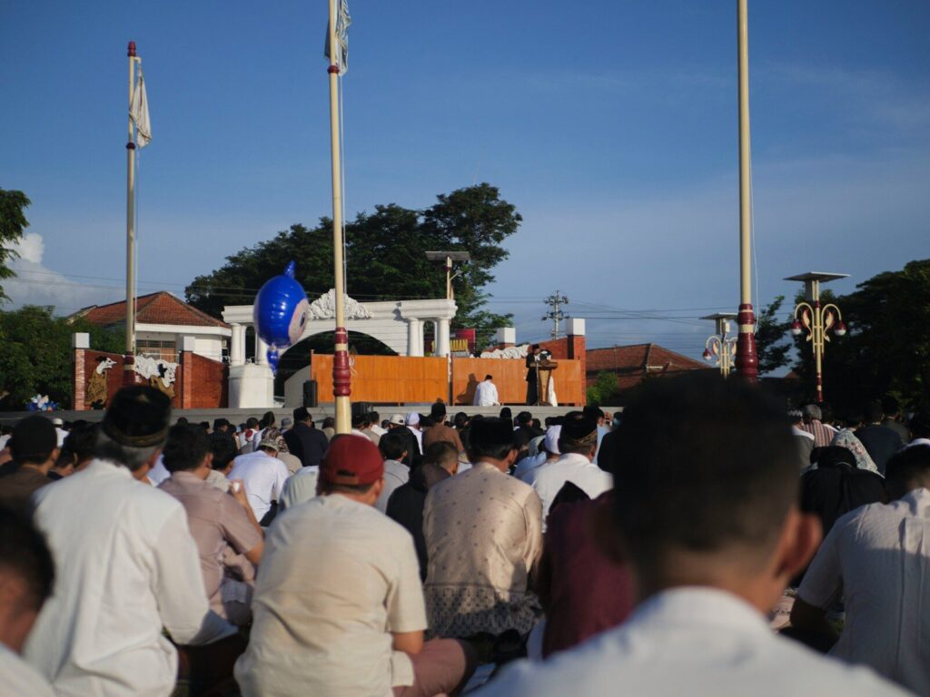 People praying outdoors at a mosque during daytime.