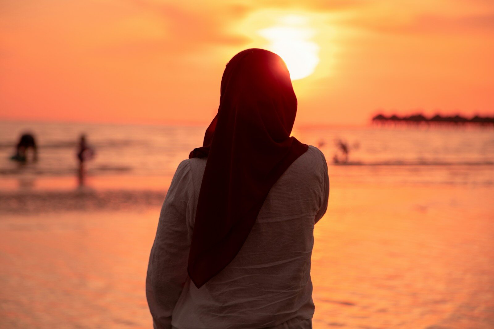 Woman in hijab watching sunset over the ocean