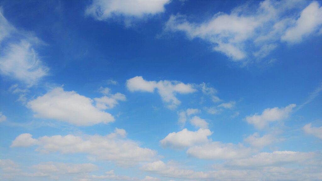 a group of people standing on a beach under a cloudy blue sky