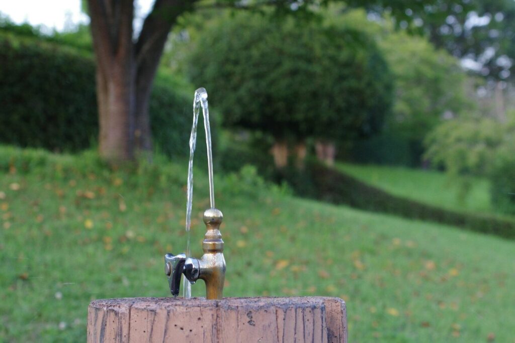 A water faucet sitting on top of a wooden post